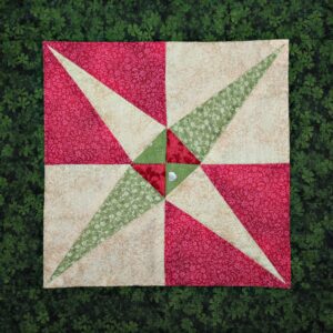 A red and green quilt on top of some grass.