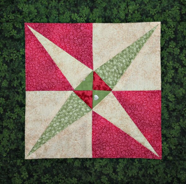 A red and green quilt on top of some grass.