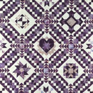 A quilt with different designs of purple and white.