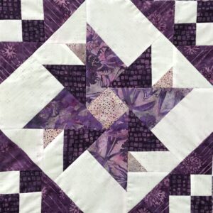 A quilt with purple and white designs on it.