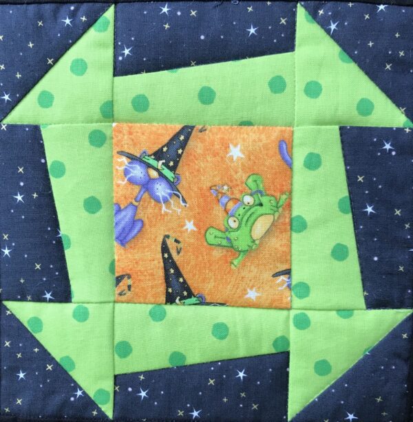 A green and black quilt with witches on it