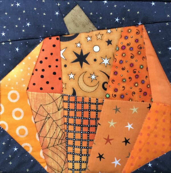 A pumpkin quilt with stars and moons on it.