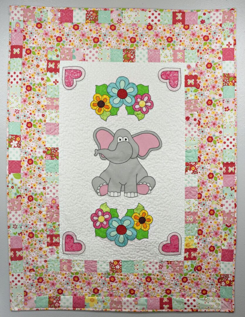 A quilt with an elephant and flowers on it.
