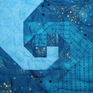 A blue quilt with gold stars and a spiral.