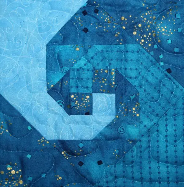 A blue quilt with gold stars and a spiral.