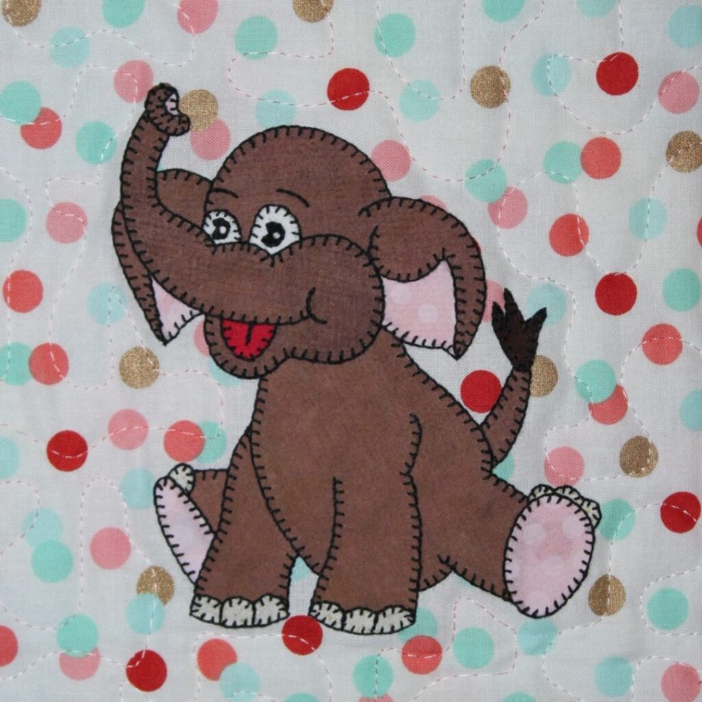 A brown elephant is standing on top of a polka dot blanket.