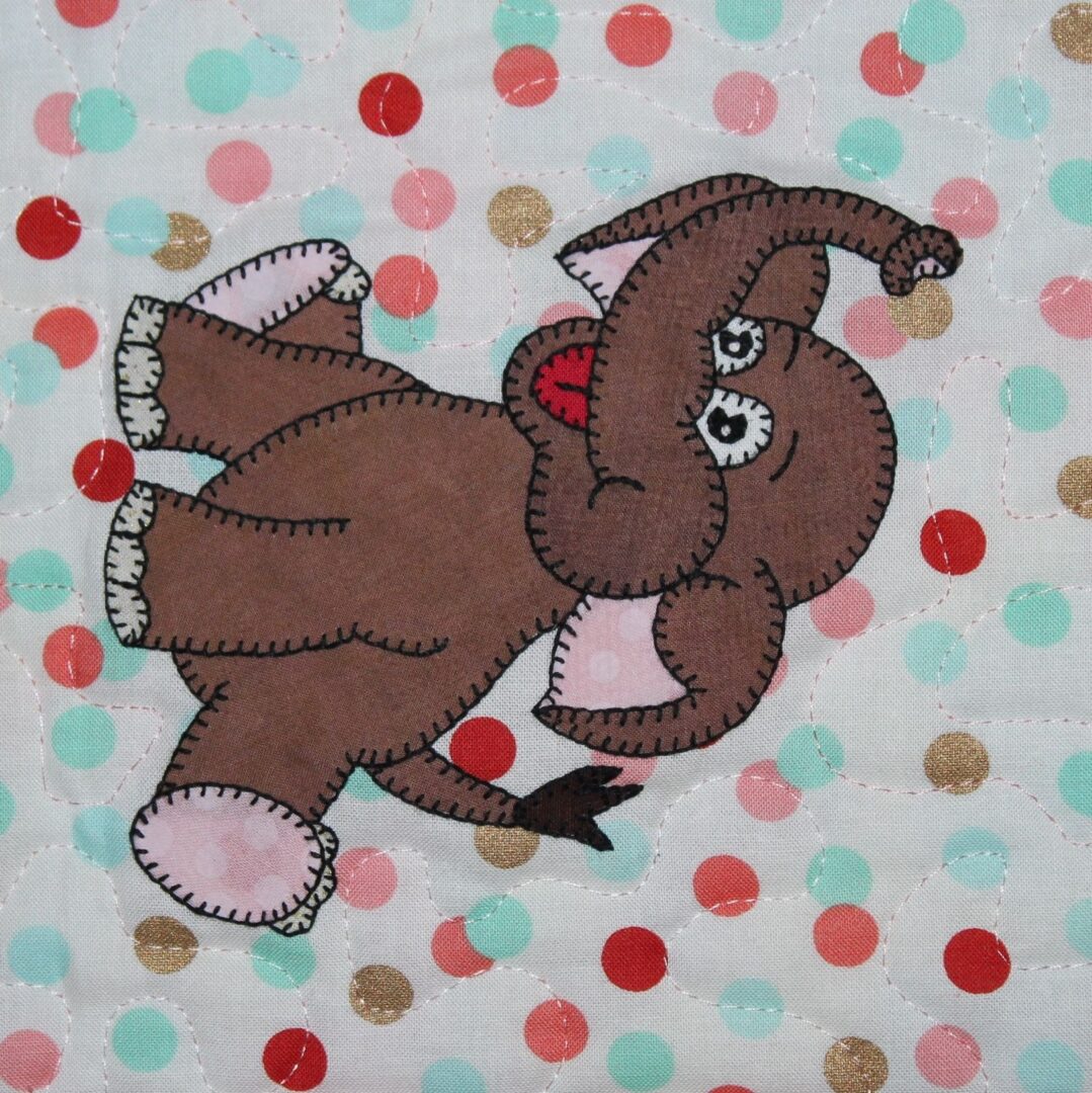 A brown elephant is standing on top of a polka dot blanket.