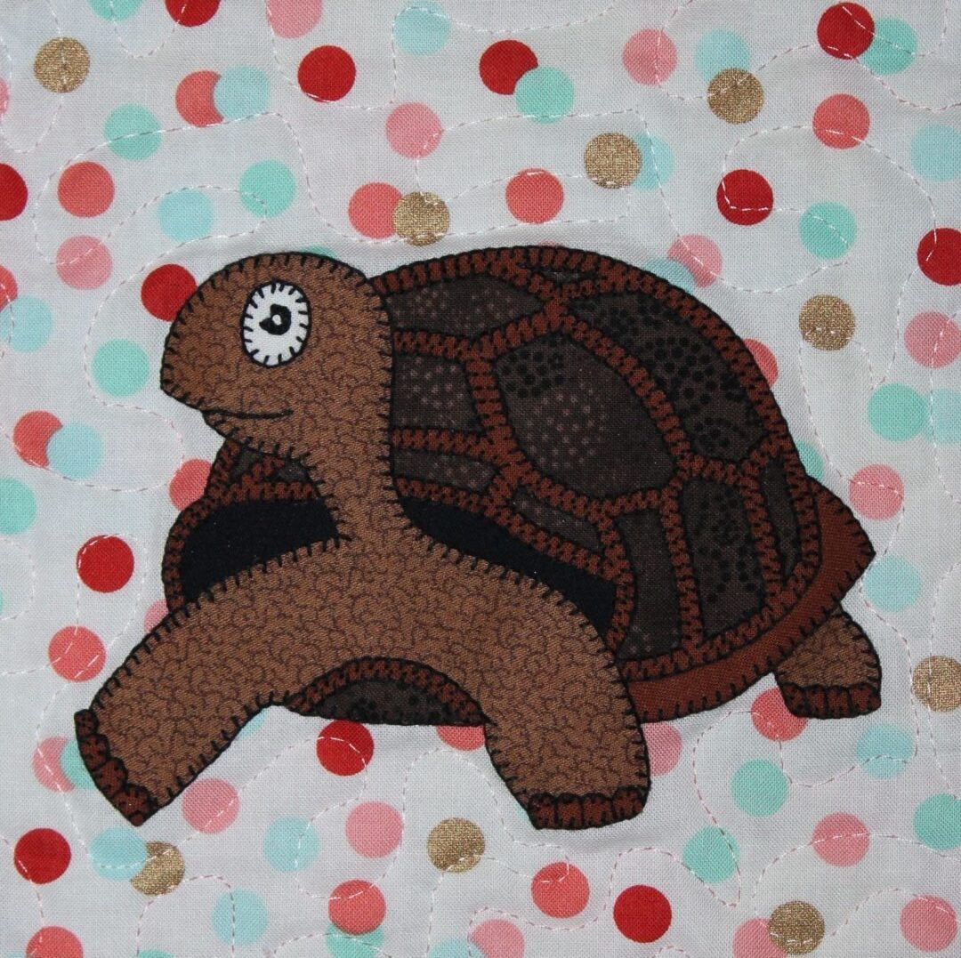 A brown turtle is sitting on top of a polka dot blanket.