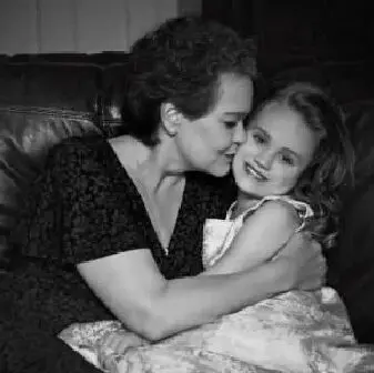 A woman and child are hugging on the couch.
