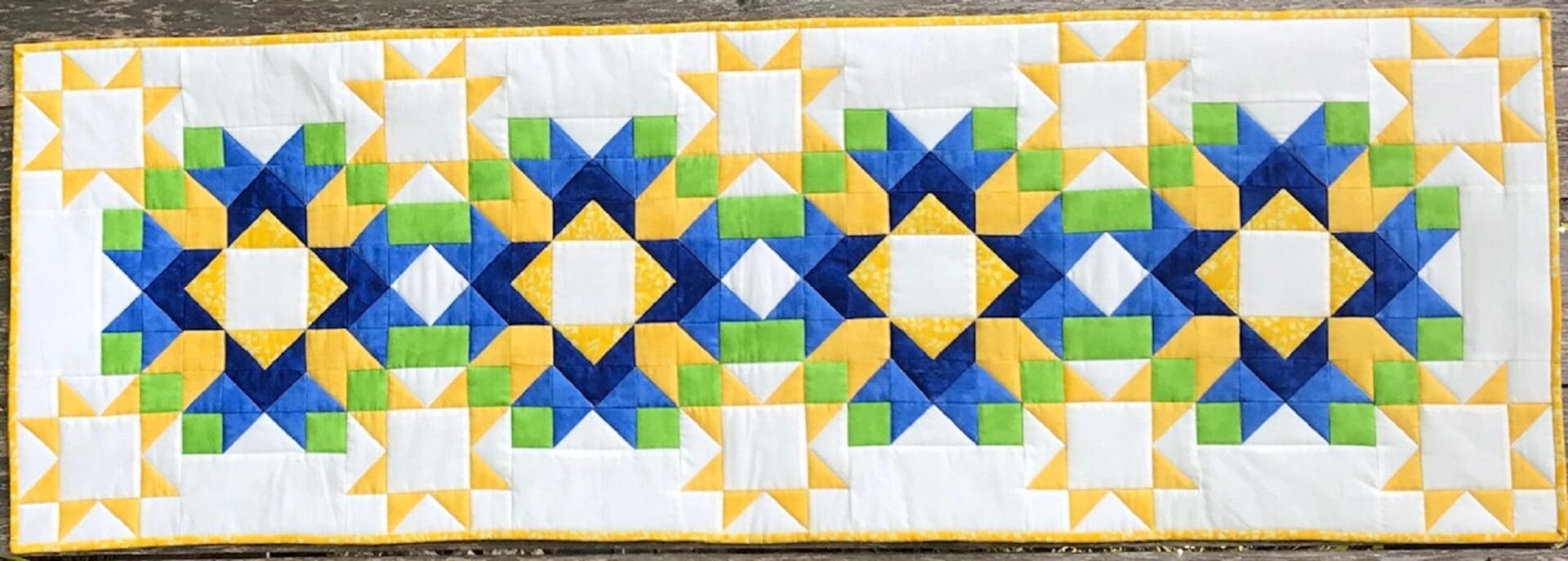 A table runner with blue, yellow and green designs.