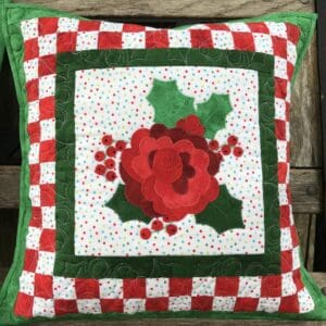 A red and green pillow with a flower on it.