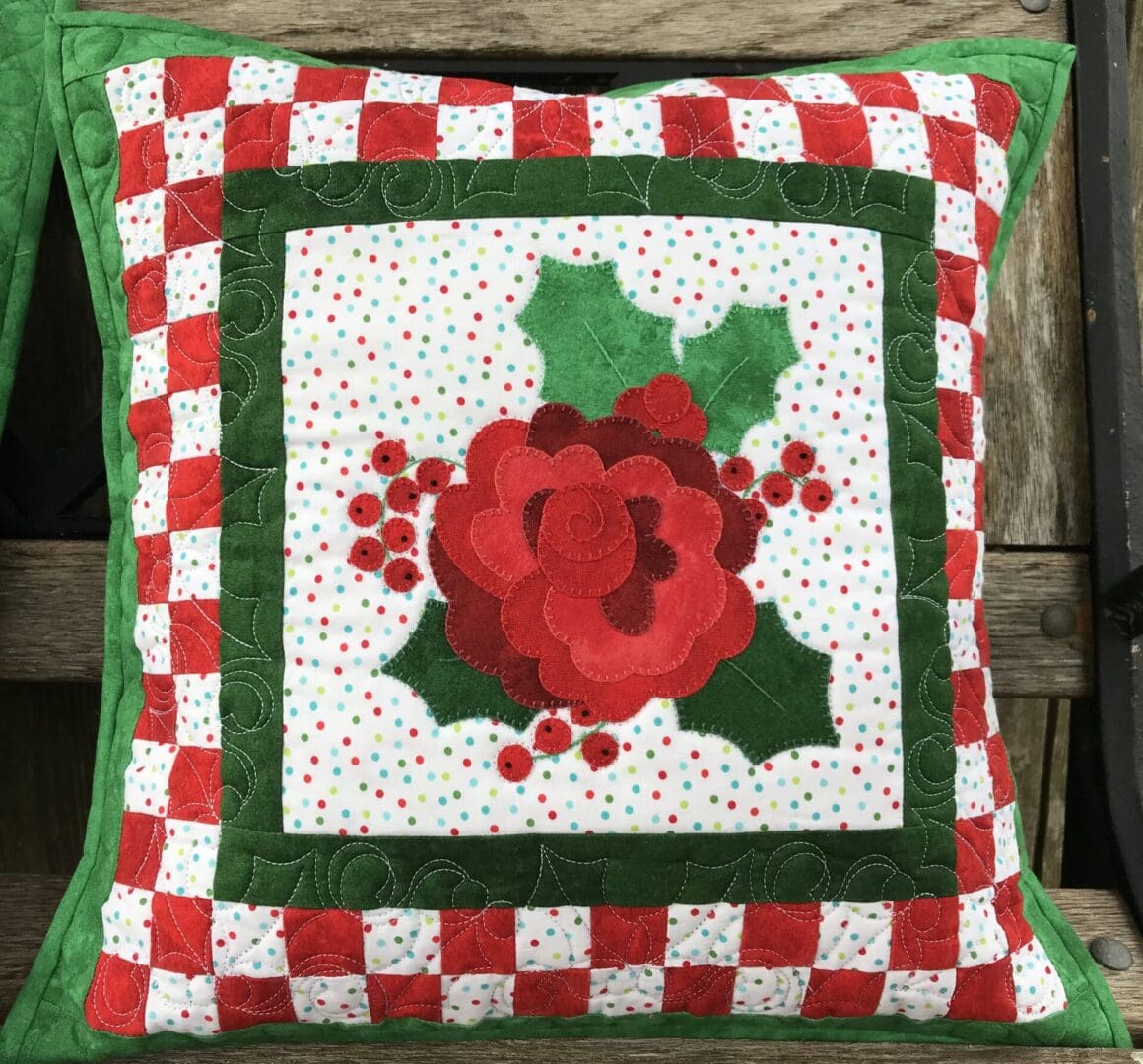 A red and green pillow with a flower on it.