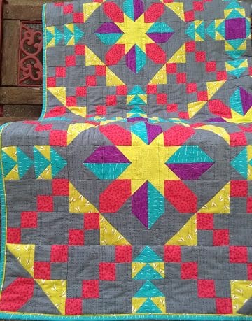 A colorful quilt is sitting on the floor.