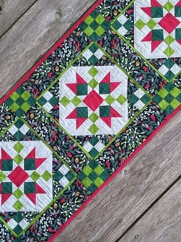 A table runner with red, green and white designs.