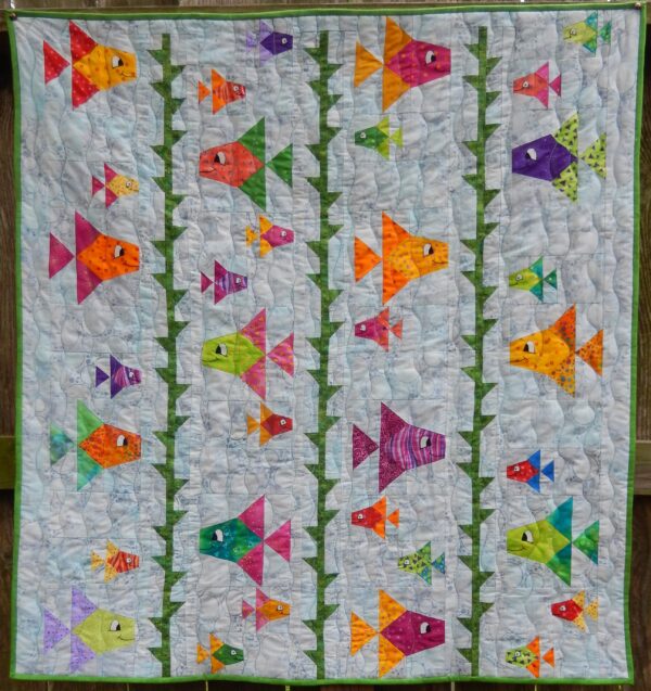 A quilt with colorful fish on it.