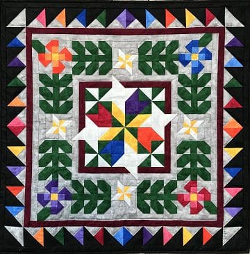 A quilt with colorful flowers and leaves on it.