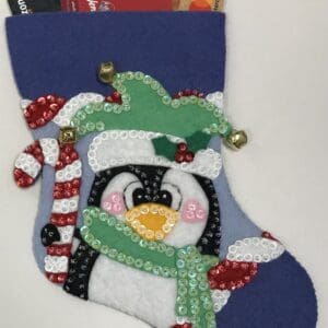 A penguin stocking with candy canes and bells.