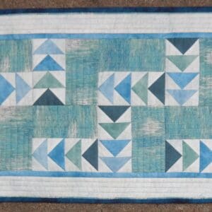 A blue and white table runner with triangles on it.