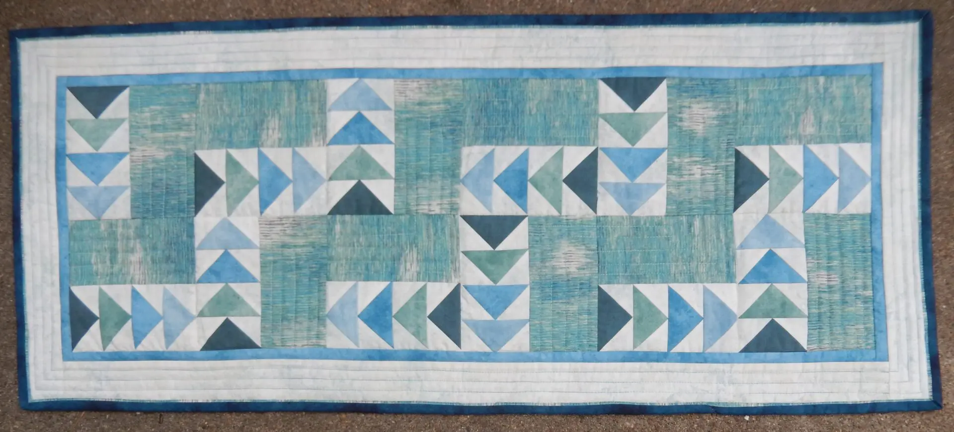A blue and white table runner with triangles on it.