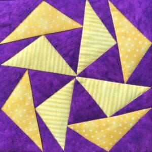 A purple and yellow quilt with triangles arranged in the center.