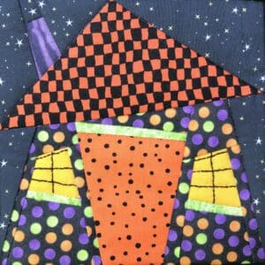 A quilt of a house with polka dots and a checkered pattern.