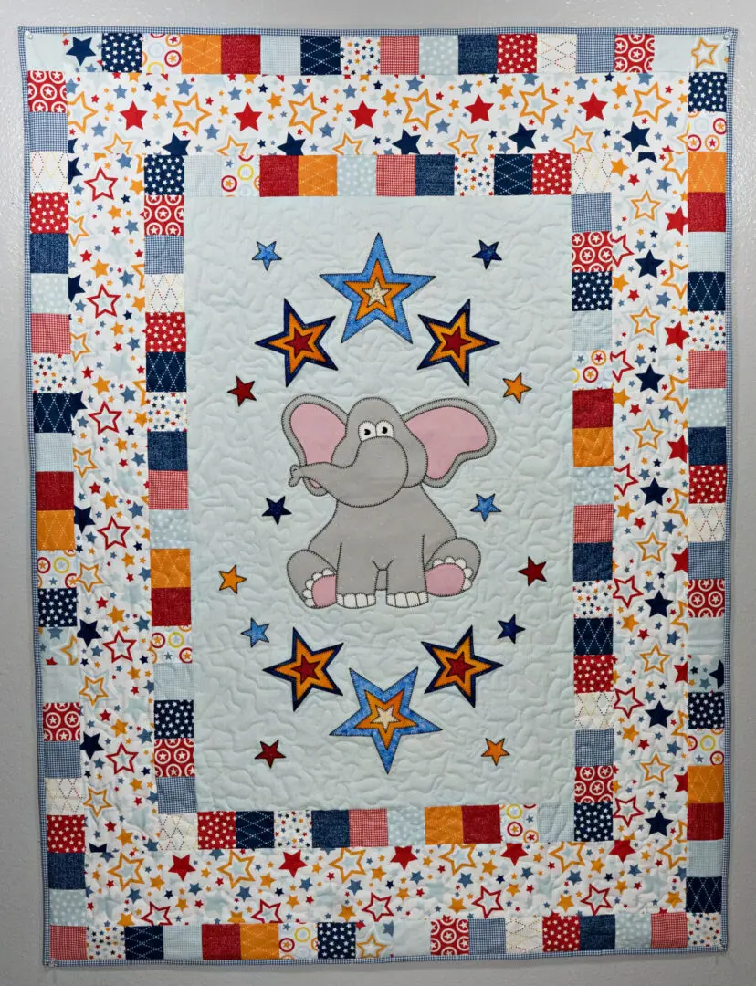 A quilt with an elephant and stars on it.