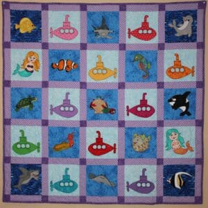 A quilt with different colored pictures of sea animals.