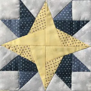 A yellow and blue star quilt block on top of a white background.