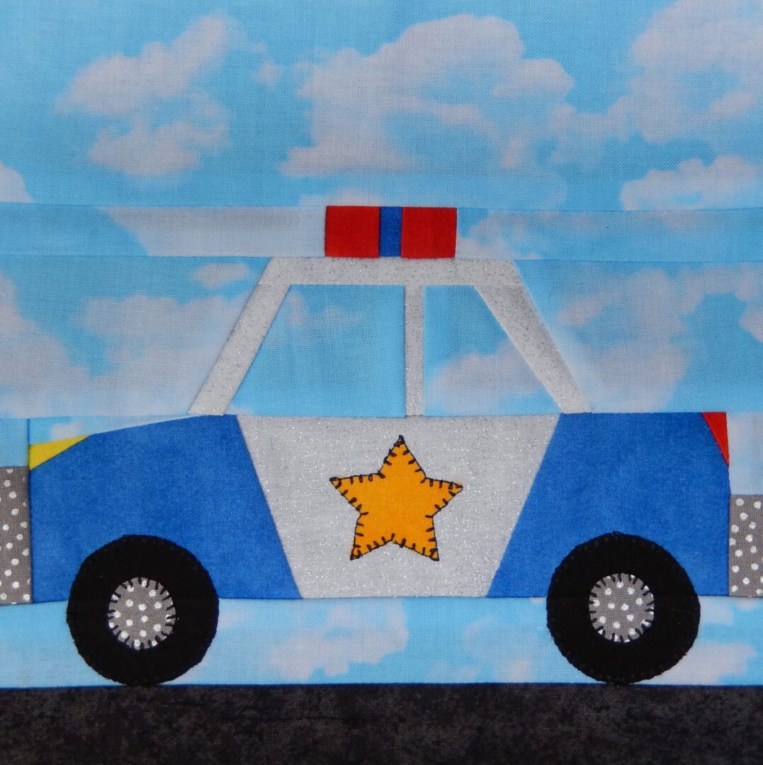 A police car quilt block with the sky in the background.