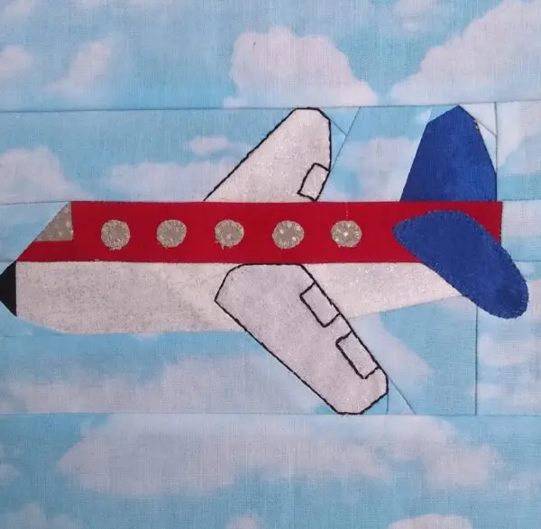 A red, white and blue airplane quilt on top of the clouds.