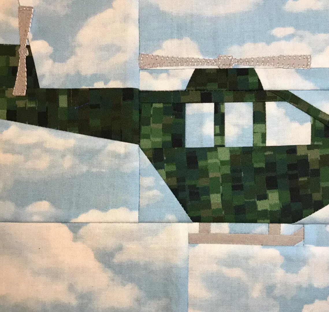 A helicopter quilt with clouds in the background.