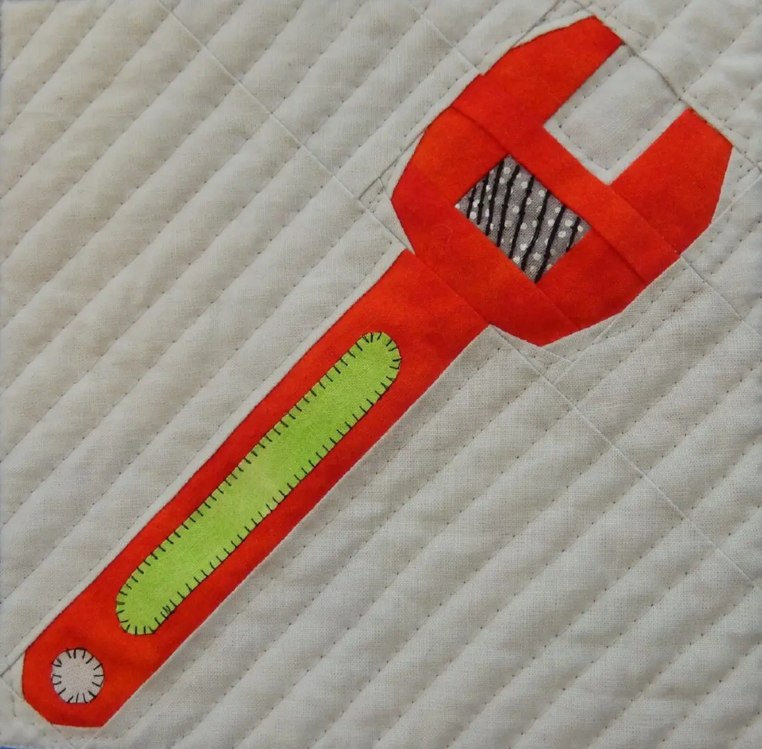 A red wrench with yellow handles on top of a white surface.