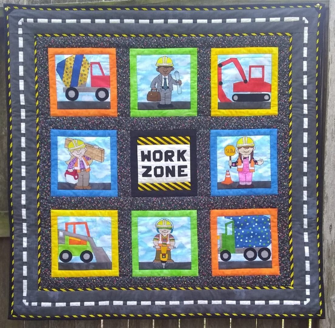 A quilt with construction themed images on it.