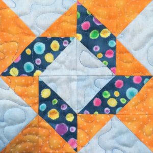An orange and blue quilt block with polka dots.