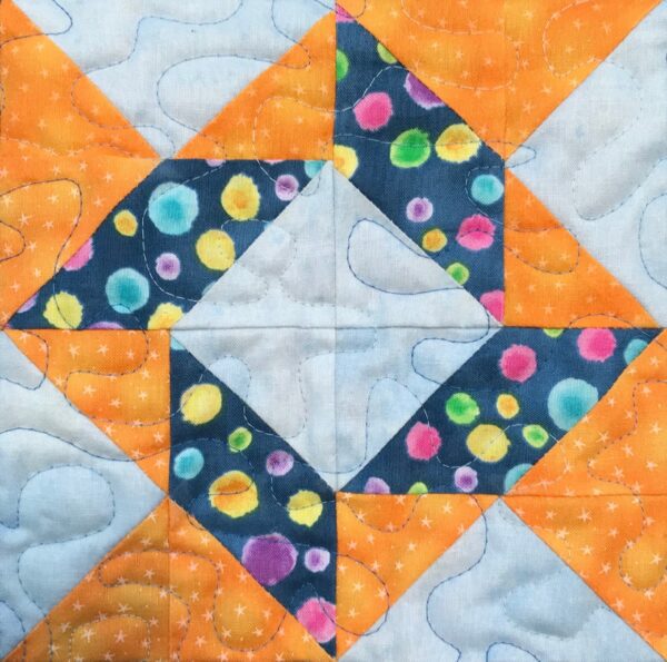 An orange and blue quilt block with polka dots.