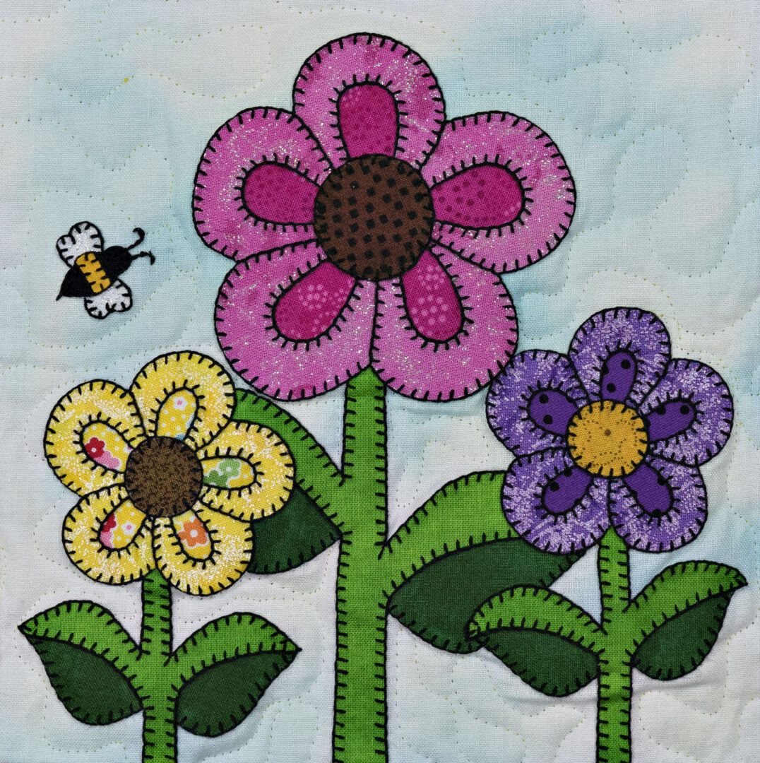 A quilt with flowers and a bee on it.