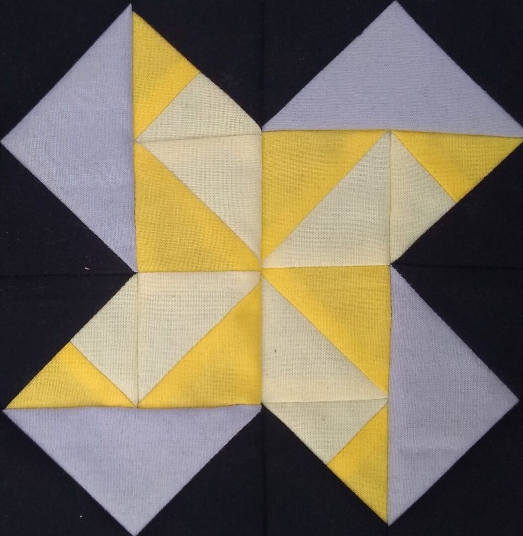A Dancing Bear quilt block with yellow and grey squares.