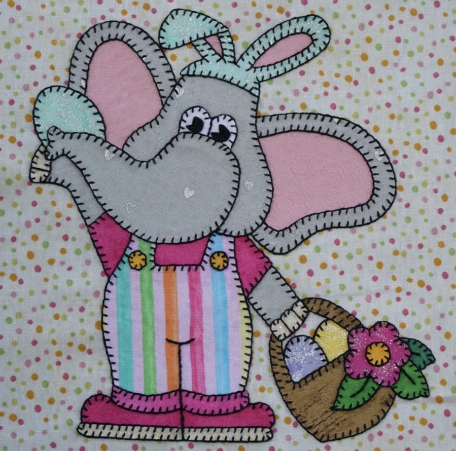 An Elephant - April with a basket of flowers on a polka dot background.