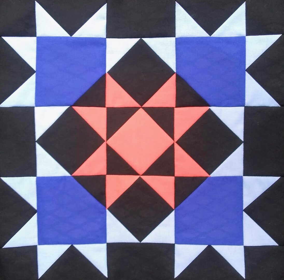 A quilt with blue and orange Star of Luxor on a black background.