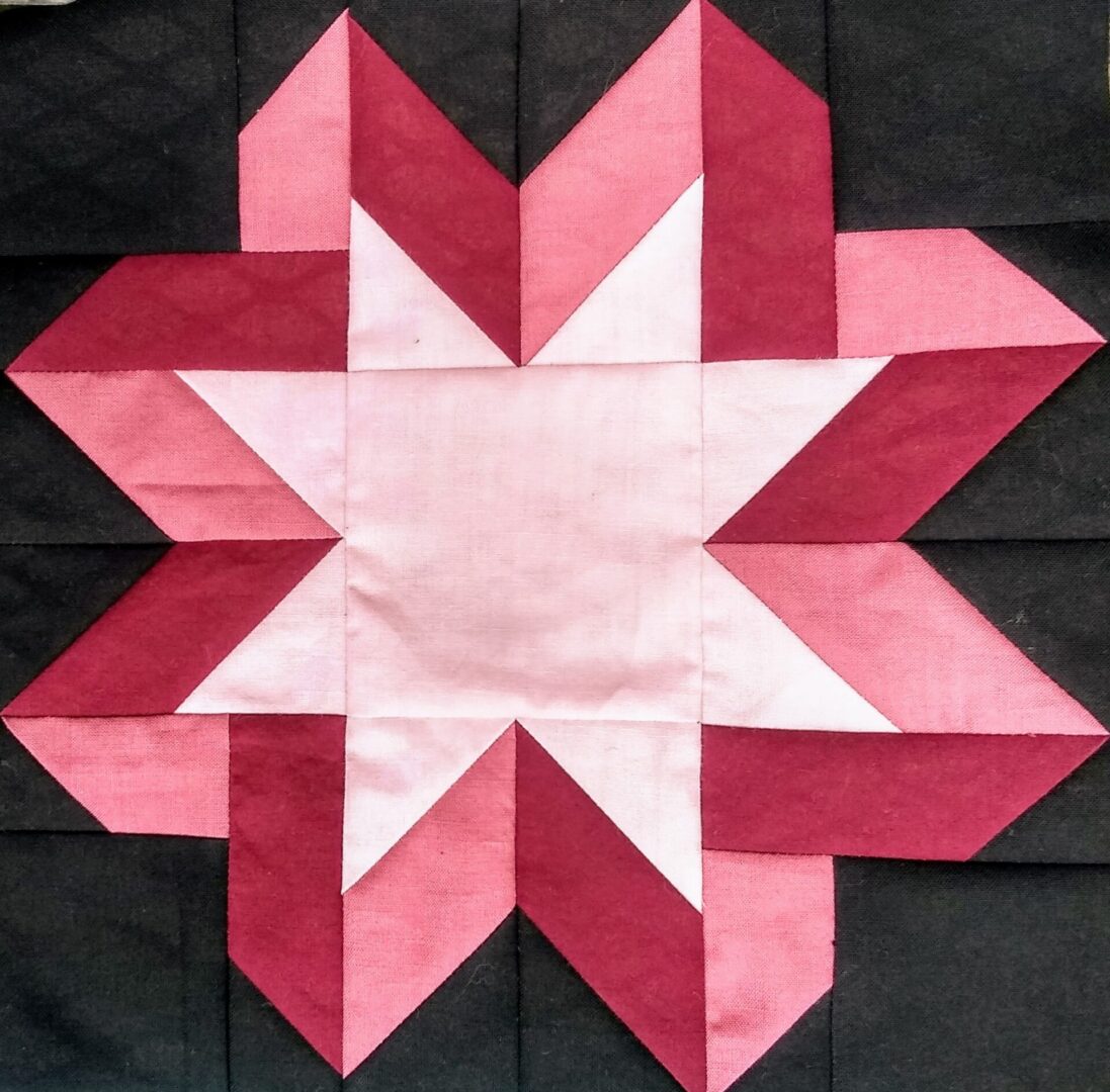 A Ribbon Star quilt block with a pink and white star.