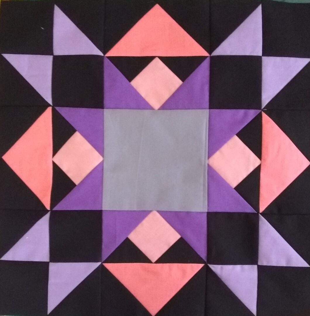 A Best of All quilt block with purple, pink and black squares.
