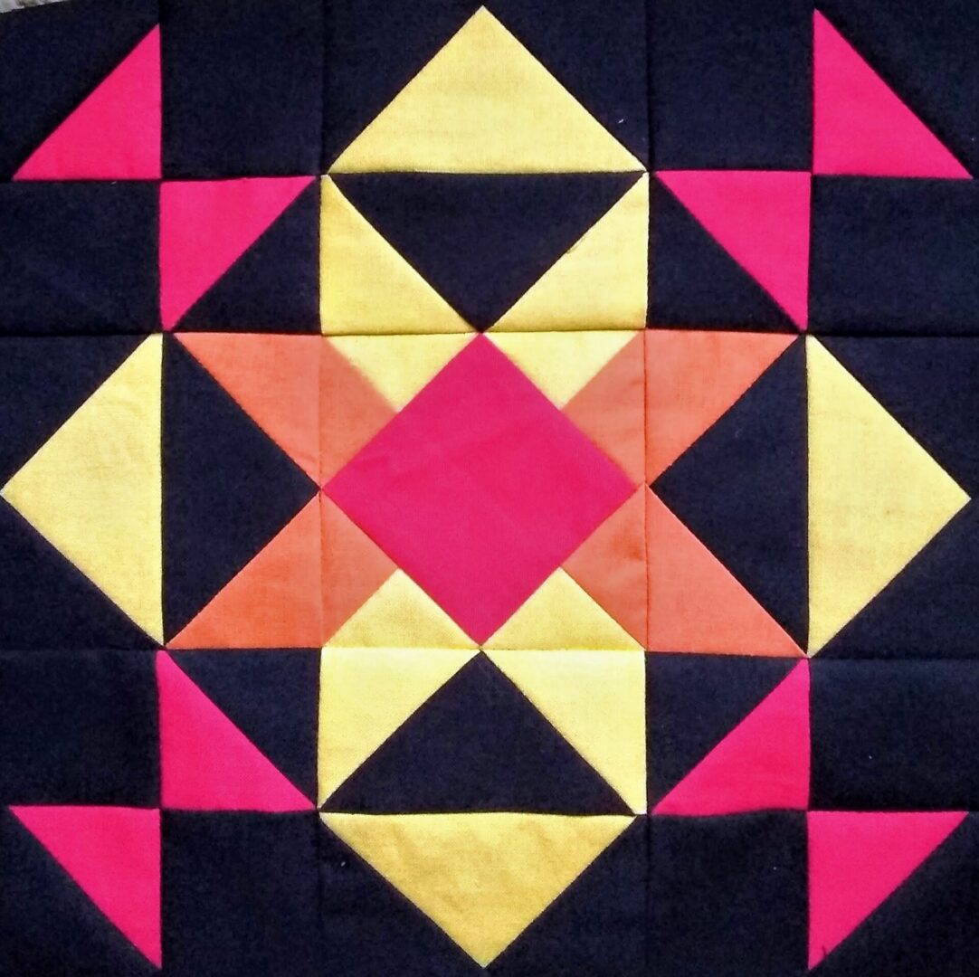 A Burning Star quilt block with a yellow, orange, and black design.