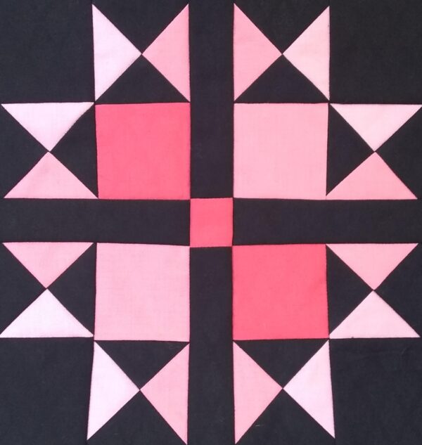 A Variable Star quilt with pink and black squares on a black background.