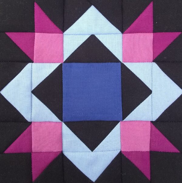 A close up of a Blueberry Pie - Small quilt block with blue and pink stars.