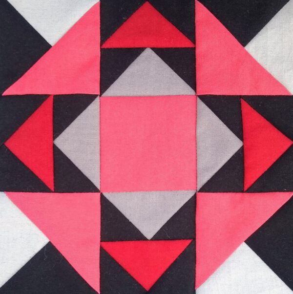 A Forest Campfire quilt block with red, black and grey squares.