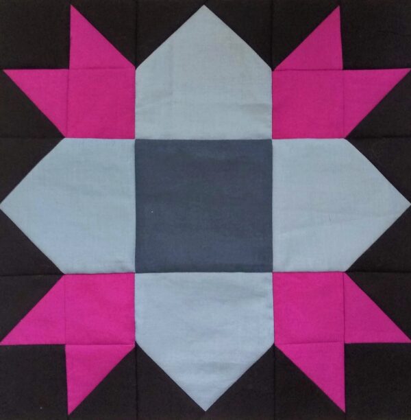 A Weathervane block with pink and black squares.