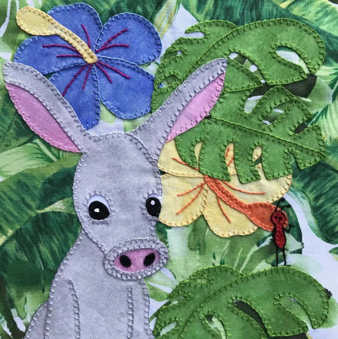 An Aardvark with flowers and leaves on a piece of fabric.