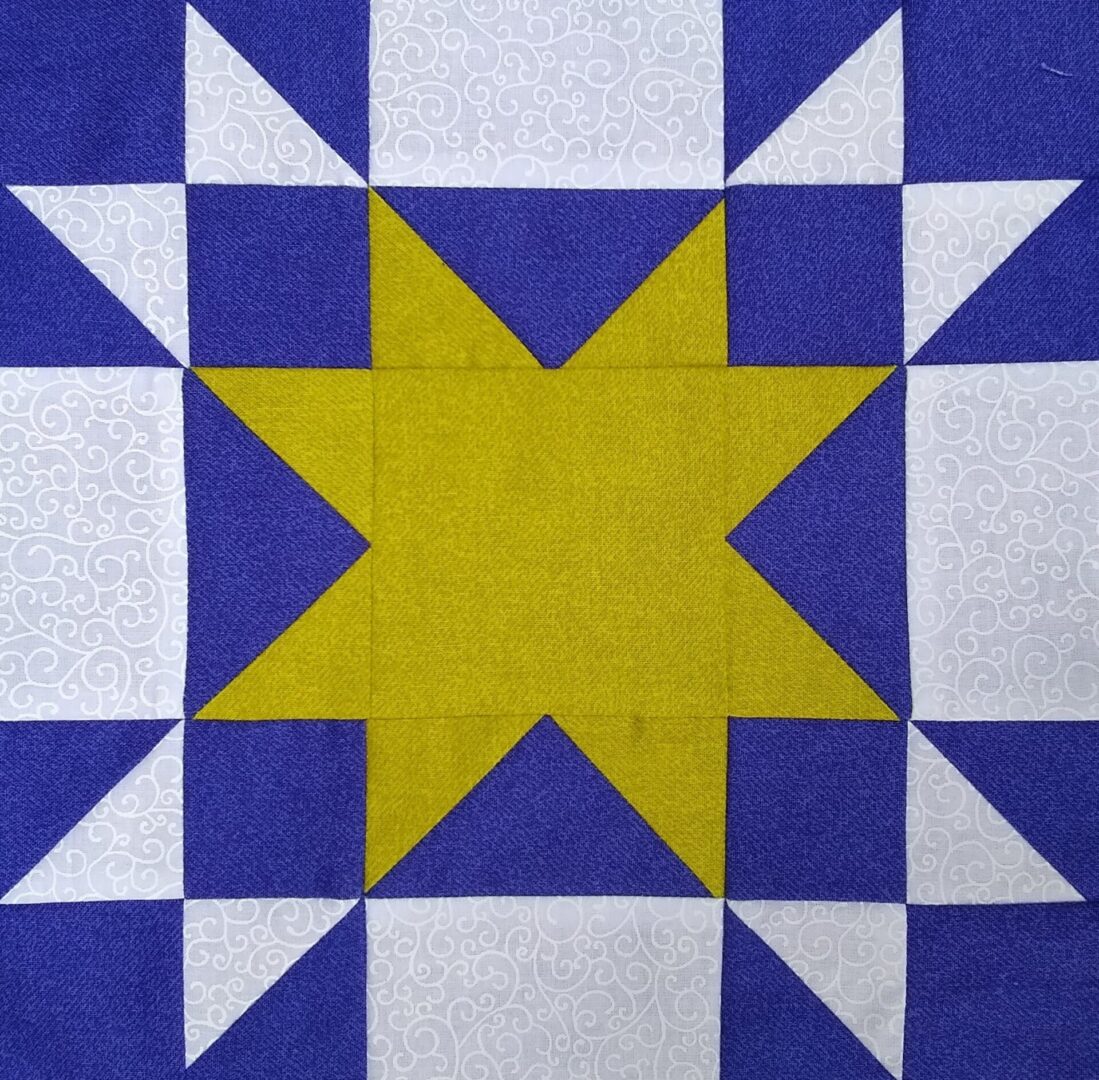 A blue and yellow Amish Star quilt block with a star in the middle.