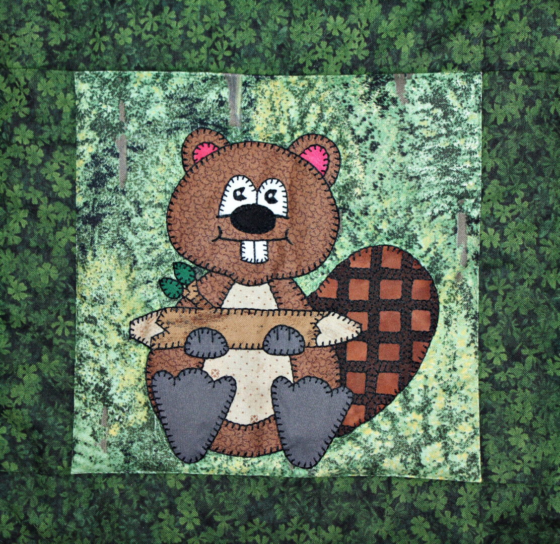 A Beaver is holding a log in a patchwork quilt.