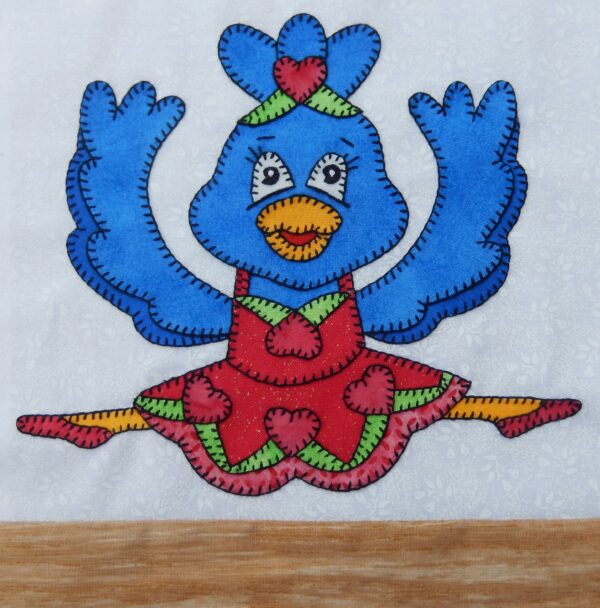 A Dance - Bird in a red dress is embroidered on a piece of cloth.